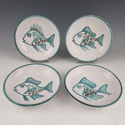 trois assiettes ornées de motifs de poissons, posées sur une table