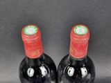 two bottles of red wine sitting next to each other on a table