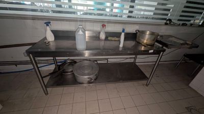 une table en acier inoxydable sur laquelle sont posés des casseroles et des poêles, dans une cuisine