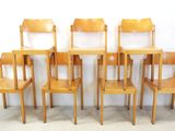 six wooden chairs that are lined up against a white wall