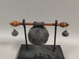 an image of a metal object with bells on a stand
