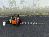 a chainsaw on the ground next to a concrete wall