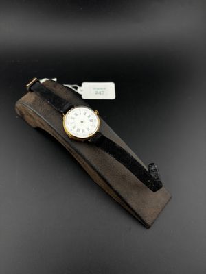 an image of a watch on a wooden stand on a black surface