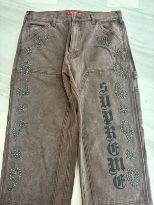un pantalon en jean orné de strass sur les côtés, posé sur un lit