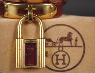 un cadenas en or orné d'une calèche tirée par des chevaux
