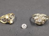 two gold rings and a diamond ring on a table next to a coin