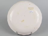 underside view of a white porcelain plate with writing on it