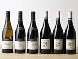 six bouteilles de vin sont alignées sur une table en bois