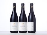 three bottles of red wine sitting on top of a table