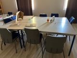 une table avec des chaises et un ordinateur portable posé dessus, dans une pièce