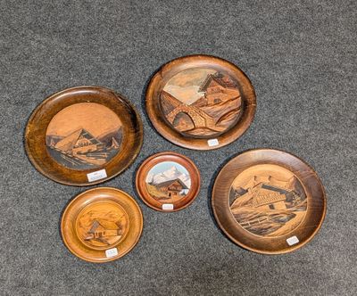 quatre assiettes en bois ornées de motifs différents, posées sur un tapis