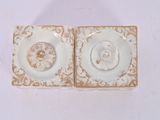 two white and gold plates with gold designs on them