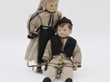 two dolls sitting next to each other on a sled