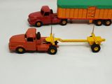 three toy trucks and a trailer on a white surface