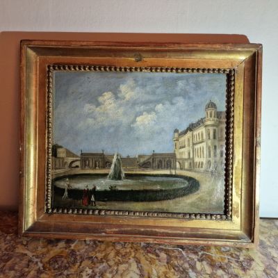une peinture à l'huile représentant une fontaine devant un bâtiment, posée sur une table