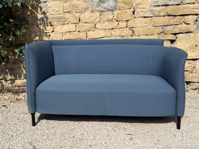 a blue couch sitting in front of a stone wall