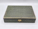 an old green box with gold trim on a white surface