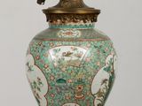 a green vase on a table with a light on it