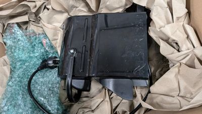 un appareil électronique noir placé à l'intérieur d'une boîte en carton