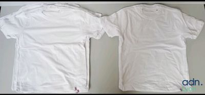 two white t - shirts sitting on top of a table next to each other