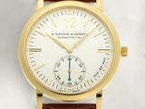 un gros plan d'une montre-bracelet en or avec un bracelet en cuir marron