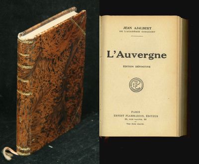 an old book sitting on top of a black table next to a small book