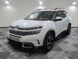 Le SUV Citrole blanc est garé dans une grande pièce.