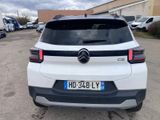 the rear end of a white car parked in a parking lot