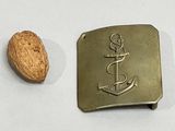 a metal buckle with an anchor on it next to a nut