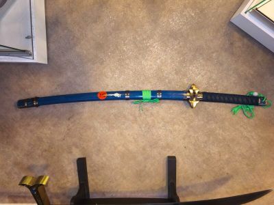 a blue samurai sword on the floor next to a pair of scissors