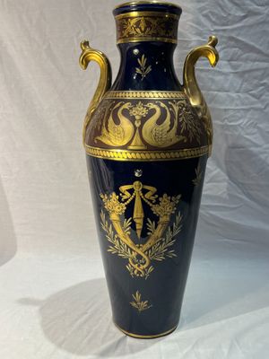 un vase bleu orné de motifs dorés sur fond blanc