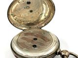 a silver pocket watch with a chain hanging from it