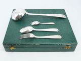 a green box with silverware in it on a white surface
