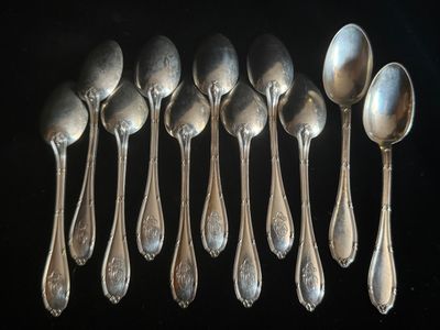 six cuillères en argent sont alignées sur une surface noire