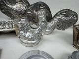 a silver plate with a chicken on it next to other silver dishes