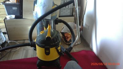a yellow and black vacuum sitting on a red rug