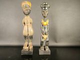 deux statues en bois représentant un homme et une femme, posées sur un fond noir