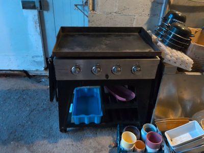 a black stove and some cups on the floor in a kitchen