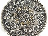 an antique silver plate with flowers and leaves on it