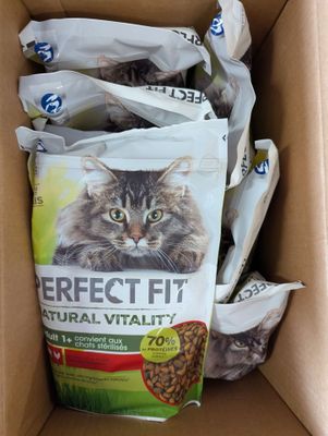 une boîte remplie de nourriture pour chat, avec un chat assis dedans