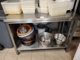 several pots and pans are stacked on a stainless steel shelf