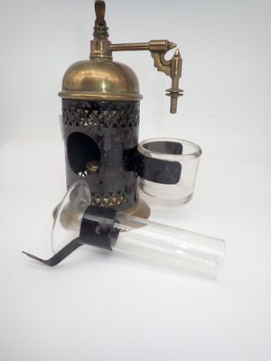 un moulin à café à l'ancienne avec un verre d'eau posé sur une surface blanche