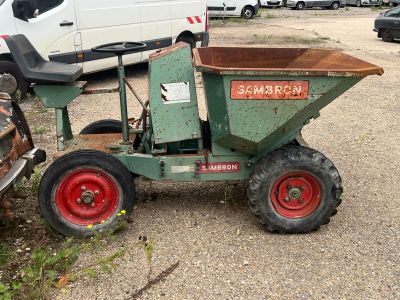 un tracteur vert avec une brouette rouge garé sur un parking