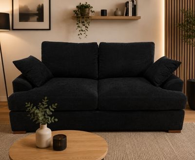 un canapé noir placé dans un salon, à côté d'une table basse