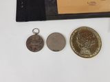 two coins and a keychain sitting on a table next to a wallet