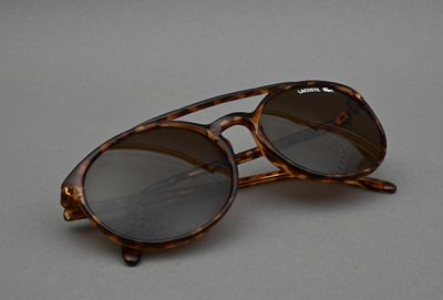 des lunettes de soleil posées sur une surface grise, avec une paire de lunettes par-dessus