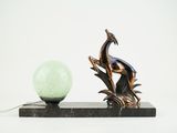 a statue of a bird sitting on a branch next to a lamp