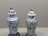 pair of blue and white vases with lids on wooden bases