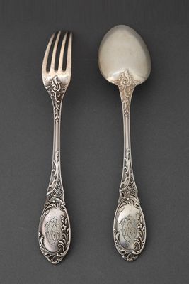 deux cuillères et une fourchette en argent sur une surface noire