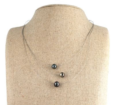 three black pearls on a silver chain on a mannequin neck